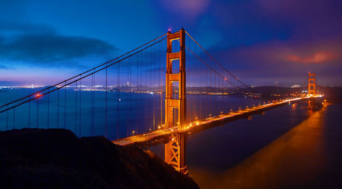 Aerial view of illuminated golden gate bridge over bay against sky at dusk