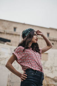 Side view of young woman standing against wall