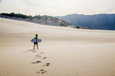 Rear view of man walking on sand dune in desert