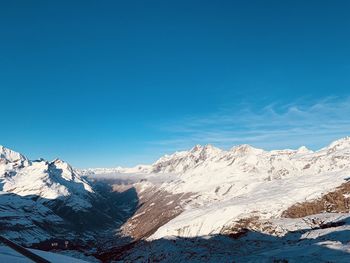 Scenic view of snowcapped mountains against blue sky