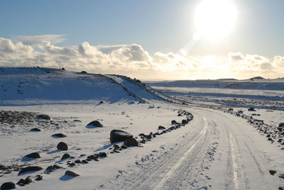 Tire tracks on snow landscape against sky