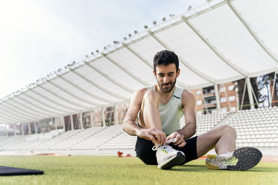 Young man sitting at sports field