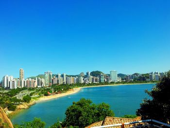 Sea and buildings against clear blue sky