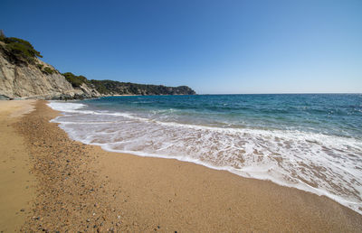 Scenic view of beach against clear blue sky