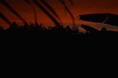 Silhouette man on field against orange sky