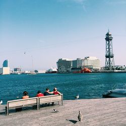 People at harbor against clear sky