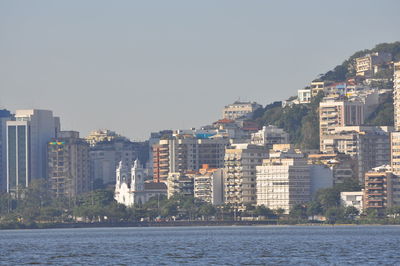 Modern buildings by sea against sky in city