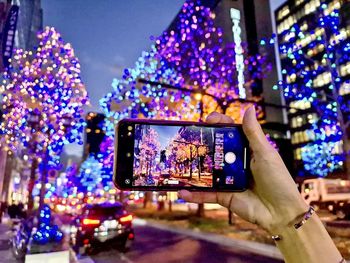 Low angle view of hand holding illuminated smart phone at night