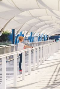 Side view of young woman standing under bridge