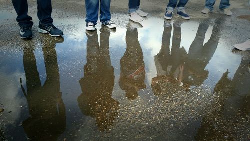 Low section of men standing on puddle during rainy season