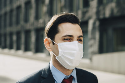 Businessman looking away against office building during pandemic