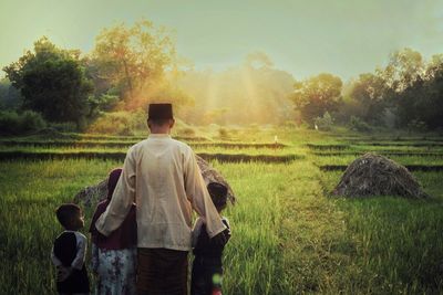 Rear view of man standing on field against sky