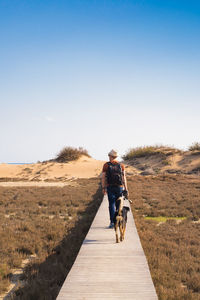 Rear view of man riding motorcycle on landscape against clear sky