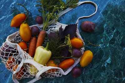 Vegetables - tomatoes, purple potatoes, sweet pepper, carrots, basil, dill in eco bag, hard shadows 