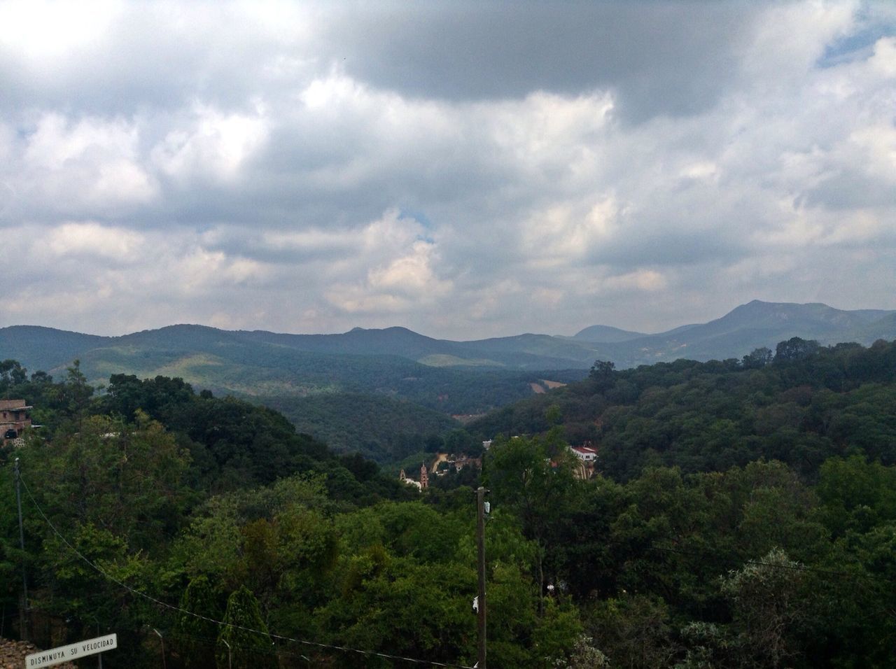 mountain, tree, mountain range, sky, scenics, tranquil scene, beauty in nature, tranquility, cloud - sky, landscape, nature, cloudy, high angle view, growth, cloud, idyllic, lush foliage, non-urban scene, outdoors, green color