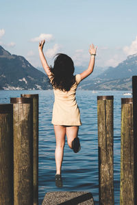 Rear view of woman with arms raised against sky