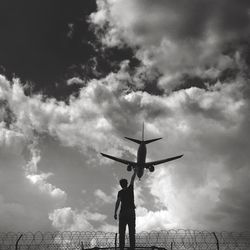 Optical illusion of man touching airplane against cloudy sky