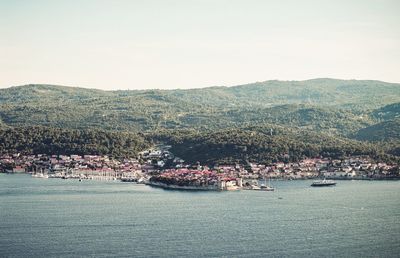 Aerial view of city by sea against clear sky