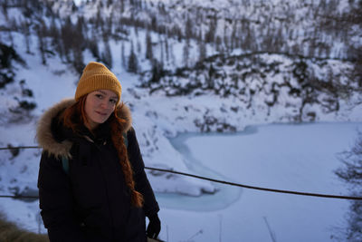 Portrait of young woman standing on snow covered field