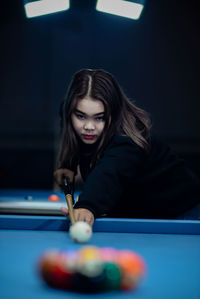 Portrait of young woman playing pool at home