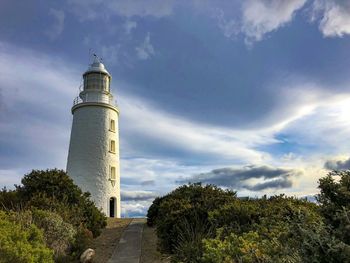 Low angle view of lighthouse by building against sky