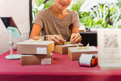 Woman small business owner packing box on table delivery to customer.