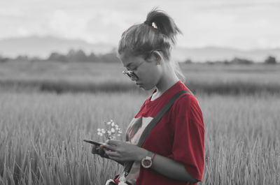 Side view of young woman looking away while standing on field