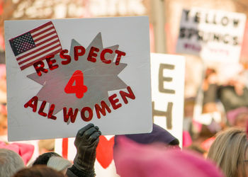 Cropped hand holding placard with text during protest in city