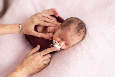 Newborn baby with pacifier tucked in a ball of wool. newborn session concept