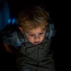 Curious toddler boy looking down in dark room