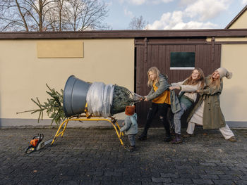 Family pulling christmas tree in front of wall