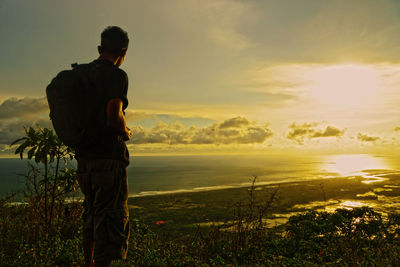 Rear view of man standing on shore against sky