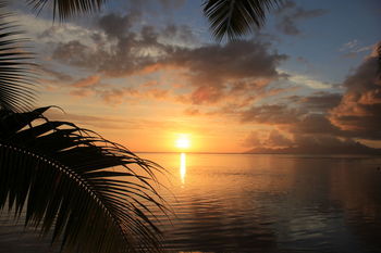 Scenic view of sea against cloudy sky during sunset