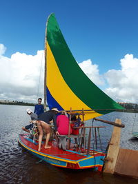 People sitting on boat in sea against sky