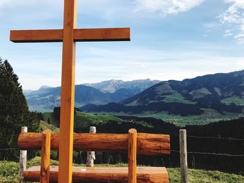 Religious cross by railing against sky