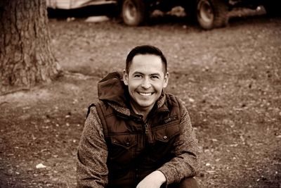 Portrait of happy man kneeling on field