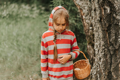 Upset or focused eight year old kid girl mushroom picker is seek for and picking mushrooms