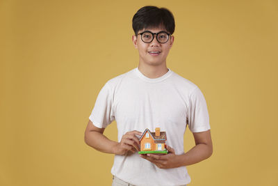 Portrait of smiling boy holding yellow against orange background