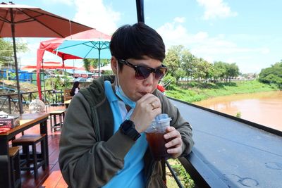 Young woman drinking drink with glass of water