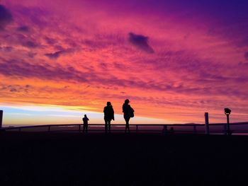 Silhouette people on beach against sky during sunset