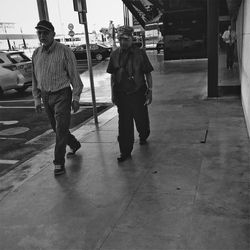 Rear view of men walking on footpath in city