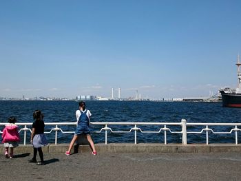 Sisters on promenade by sea against sky