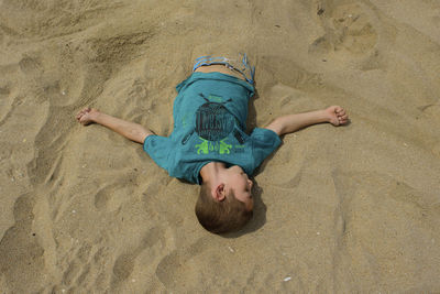 High angle view of boy buried in sand at beach