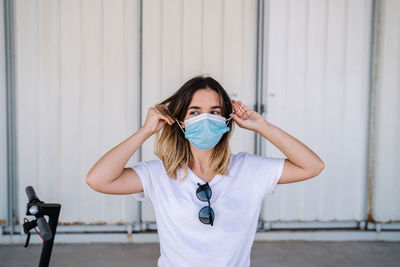 Portrait of young woman standing against wall