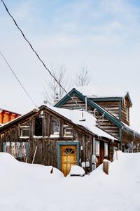 Houses by snow covered building against sky