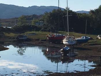 Boats on sea by mountains against sky