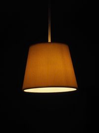 Low angle view of illuminated electric lamp against black background