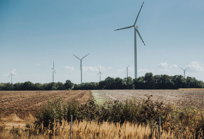 Wind turbines on field against clear sky