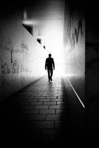 Rear view of man walking on footpath in tunnel
