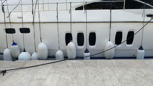 Side view of white boat  with windows and buoys moored 